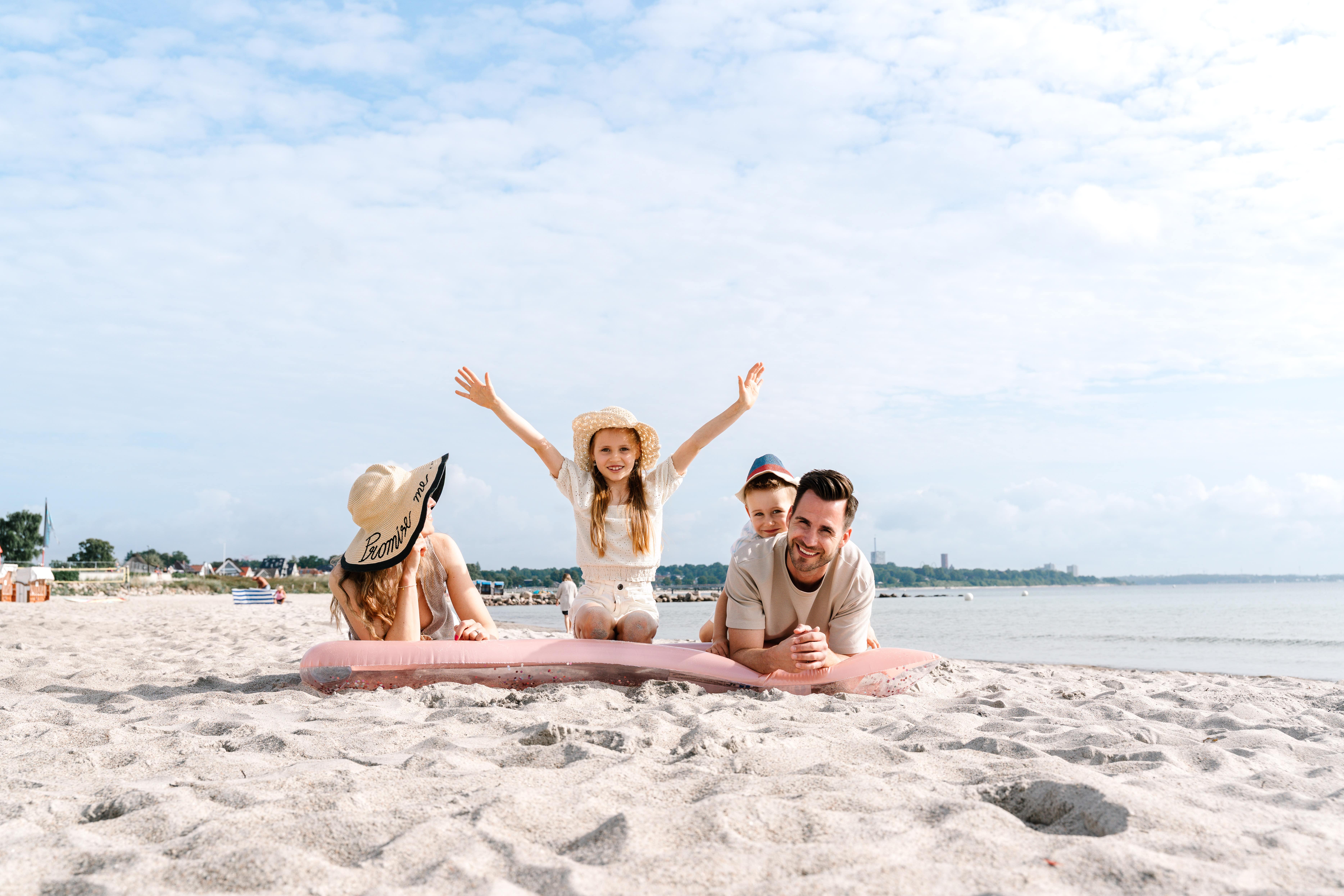 Familie sitzt am Strand und freut sich